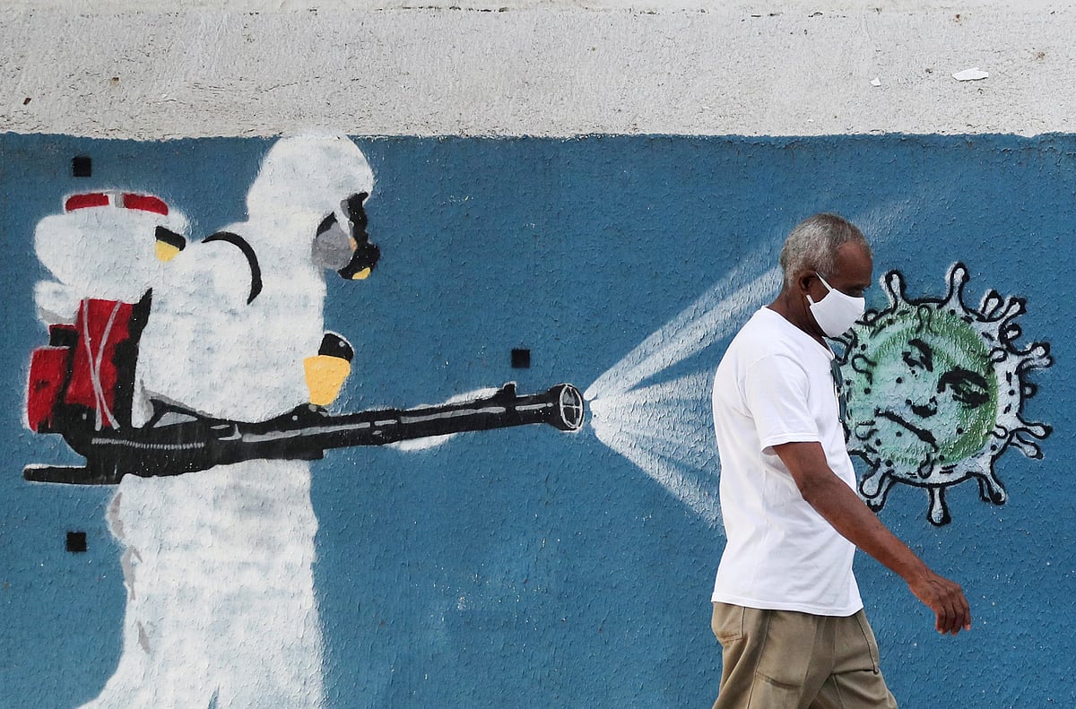 A man walks next to a graffiti that depicts a cleaner wearing protective gear spraying viruses with the face of Brazil's president Jair Bolsonaro amid the coronavirus disease (COVID-19) outbreak, in Rio de Janeiro, Brazil, 12 June 2020.