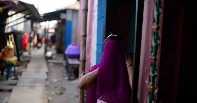 A sex worker hides her face behind a veil