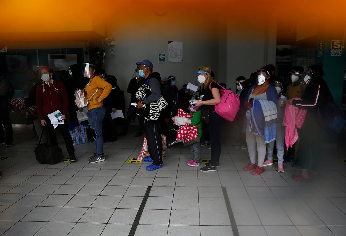 Passengers wearing face masks and face shields are seen through a window as they wait to board buses, during the outbreak of the coronavirus disease (COVID-19), in Lima, Peru on 15 July.