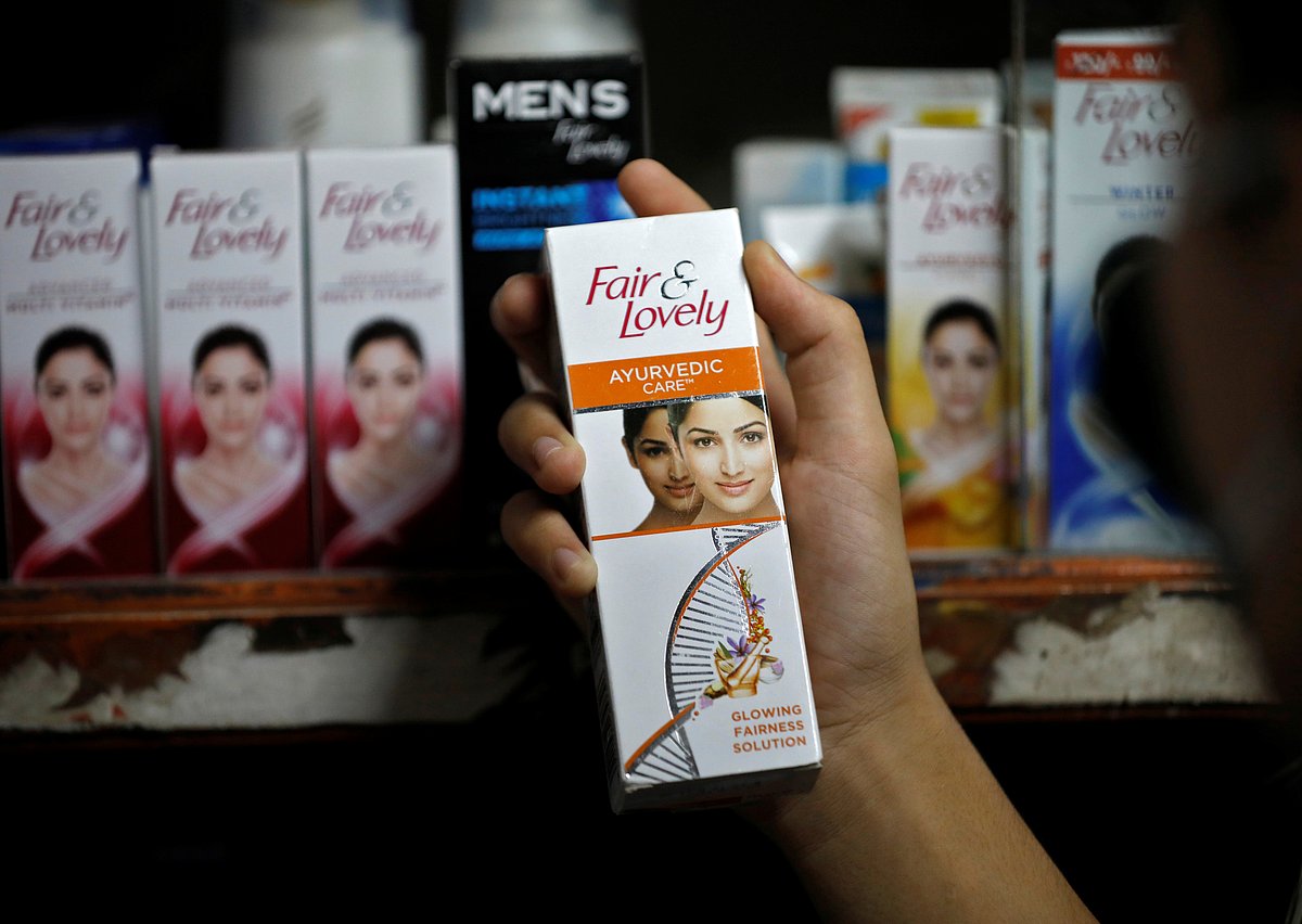 A customer picks up "Fair & Lovely" brand of skin lightening product from a shelf in a shop.