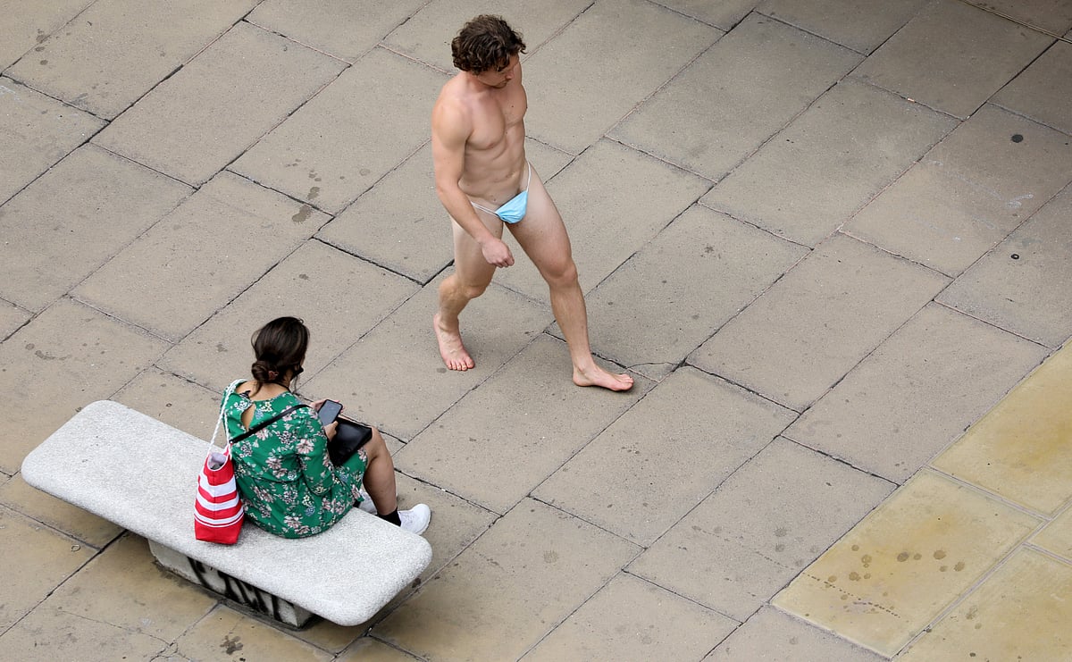 A man wearing a surgical mask as G-string walks past a woman, as the spread of the coronavirus disease (COVID-19) continues, on Oxford Street in London, Britain, 24 July 2020.