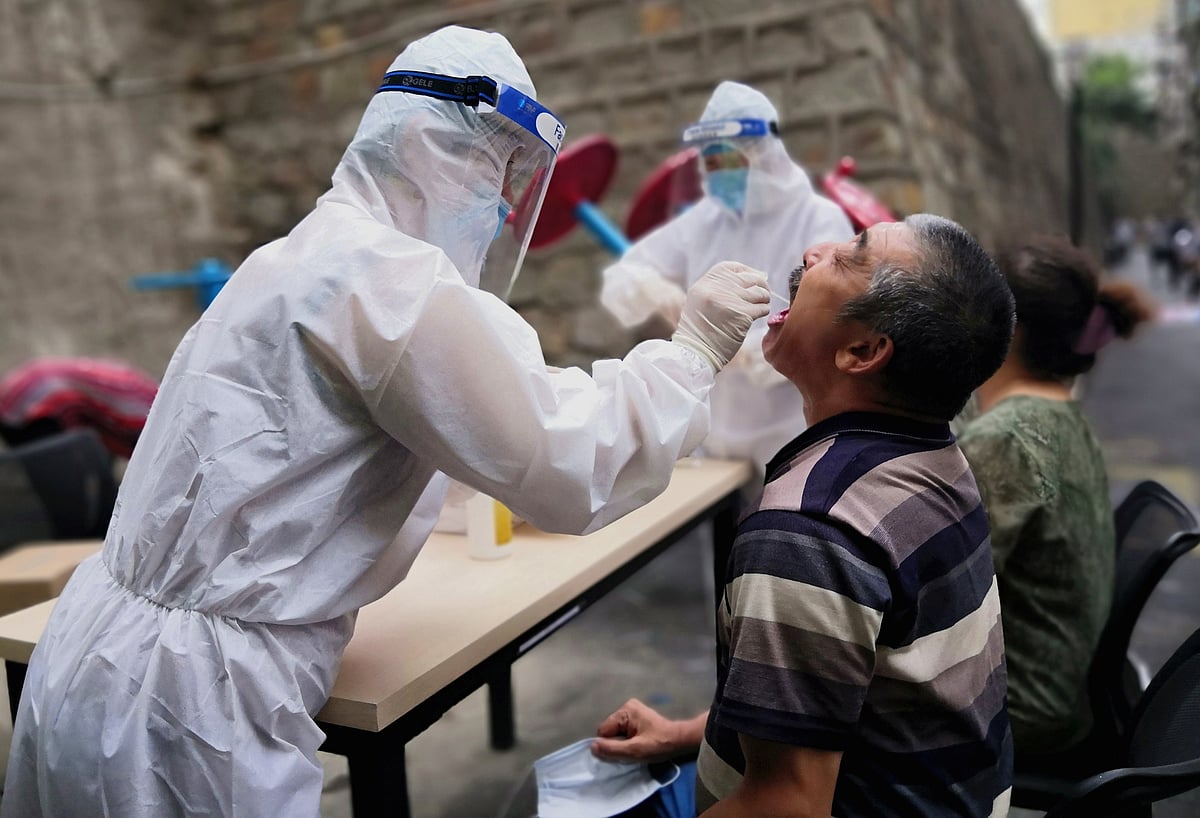 A medical worker in protective suit collects a swab from a man to conduct free nucleic acid tests for residents in the residential compound, after new cases of coronavirus disease (COVID-19) were found in Urumqi, Xinjiang province, China on 19 July.