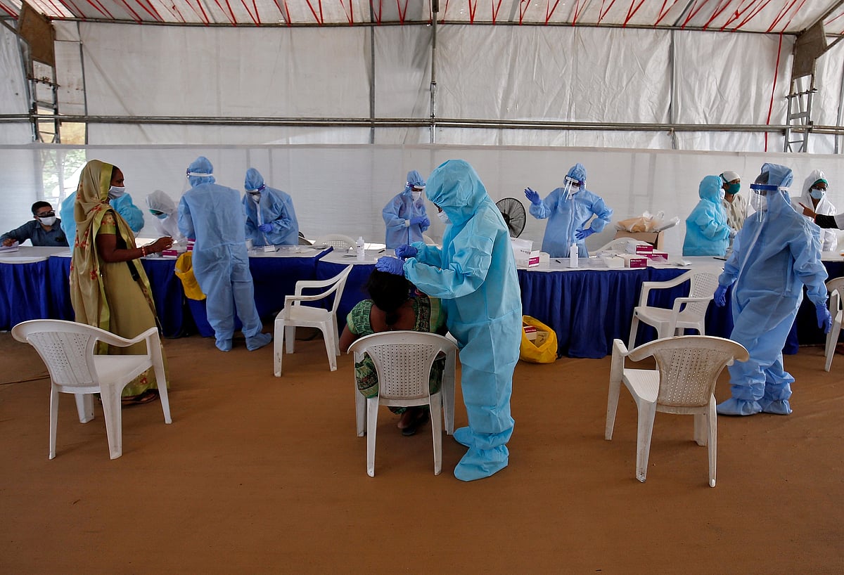 A healthcare worker wearing protective gear takes a swab from a woman for a rapid antigen test, amidst the coronavirus disease, COVID-19, outbreak, at a check-up point in Ahmedabad, India, on 17 July 2020