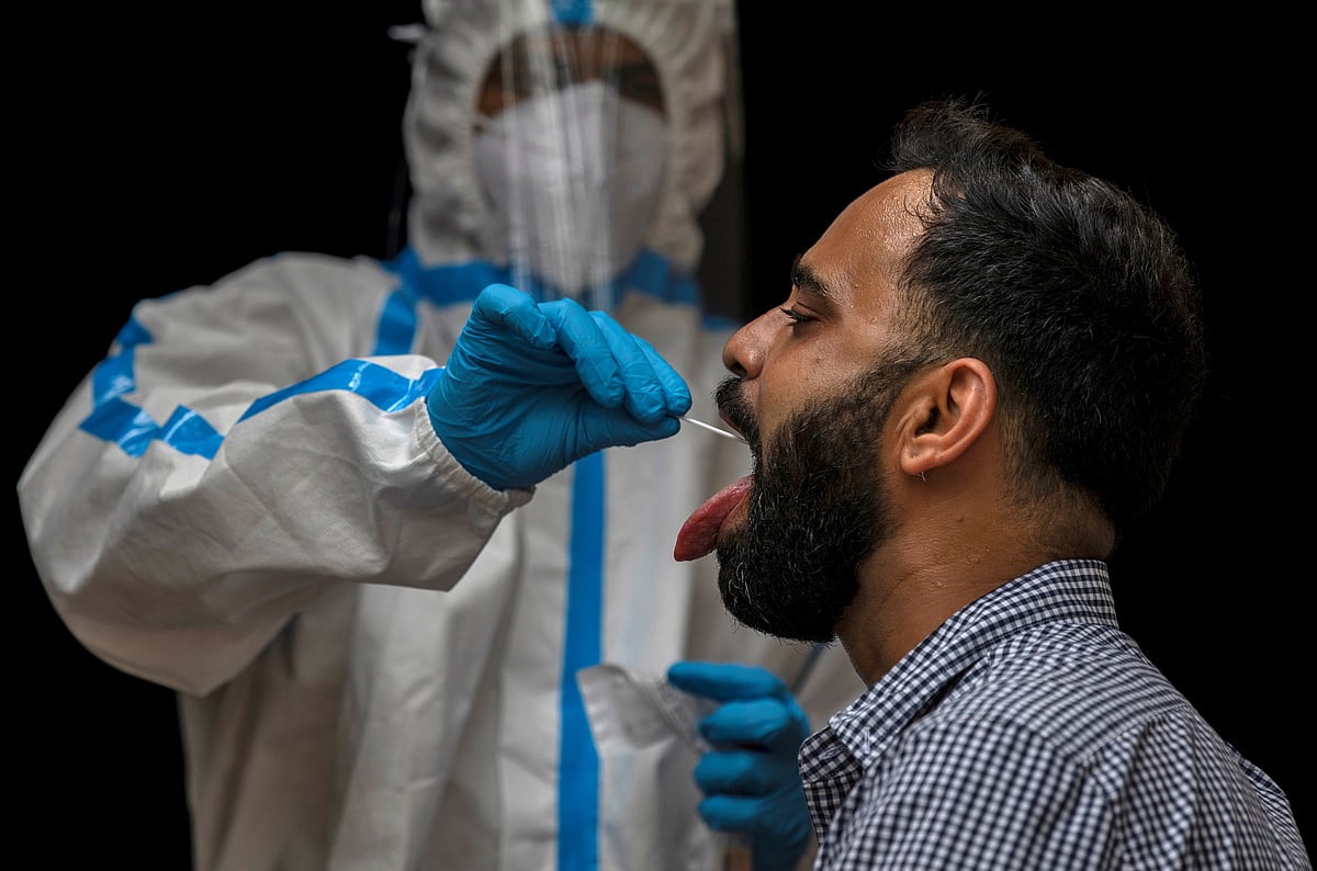 A health worker in personal protective equipment (PPE) collects a sample using a swab from a person to conduct tests for the coronavirus disease (COVID-19), amid the spread of the disease, in New Delhi, India on 10 July 2020