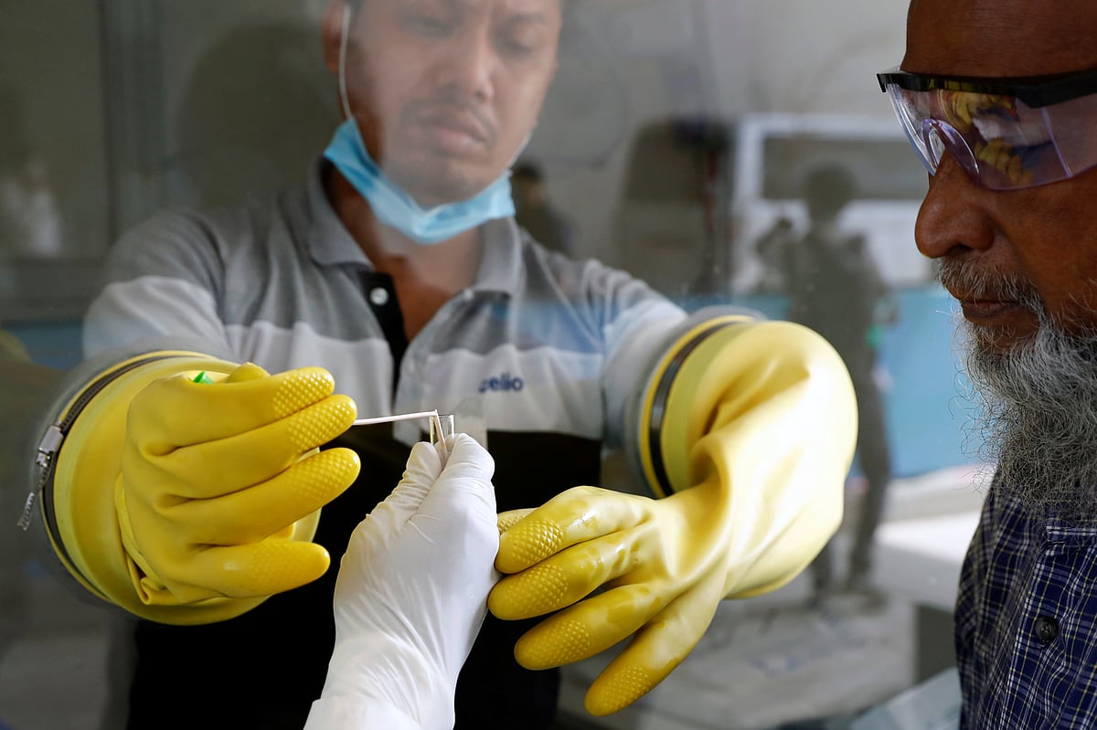 A health worker collects a swab of a man during a coronavirus test in the Mugda Medical College and Hospital as the coronavirus disease (COVID-19) outbreak continues in Dhaka, Bangladesh, 2 July 2020
