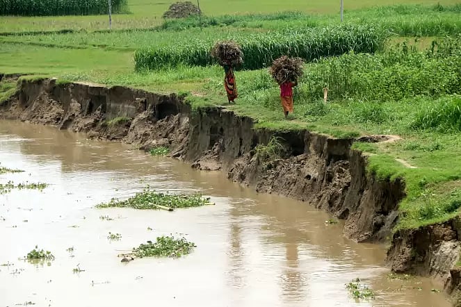 People walk along river bank eroded due to monsoon flood in Bogura's Jorgachha, Sariakandi on 1 July 2020.