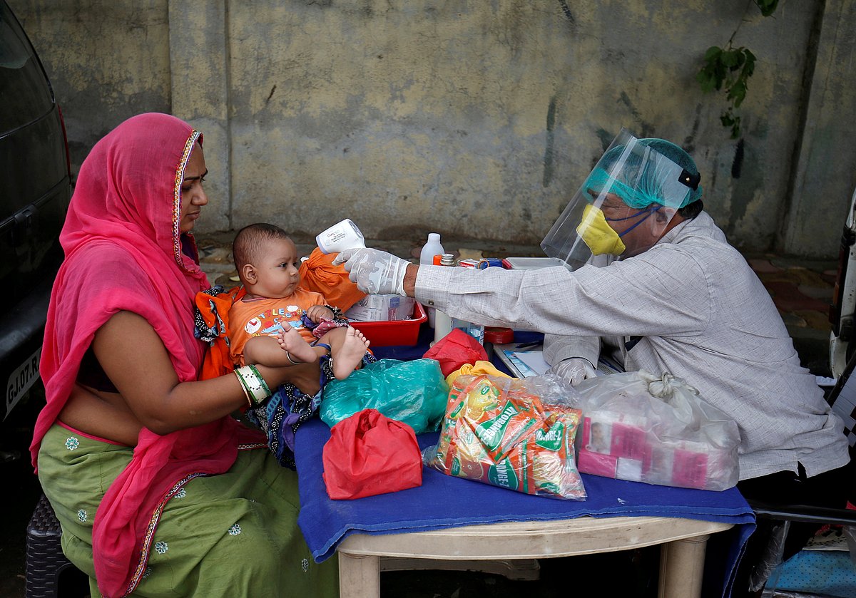 A doctor wearing a protective face shield uses an infrared thermometer to measure the temperature of a child at his mobile health clinic, after his clinic and its adjoining areas were declared a micro-containment zone, after authorities eased lockdown restrictions that were imposed to slow the spread of the coronavirus disease (COVID-19), in Ahmedabad, India on 15 June.