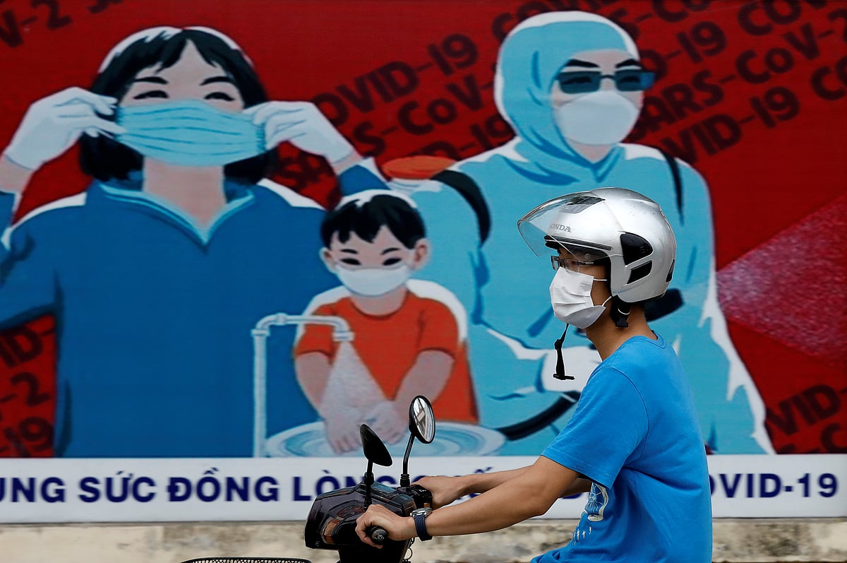 A man wears a protective mask as he drives past a banner promoting prevention against the coronavirus disease (COVID-19) in Hanoi, Vietnam 31 July 2020.
