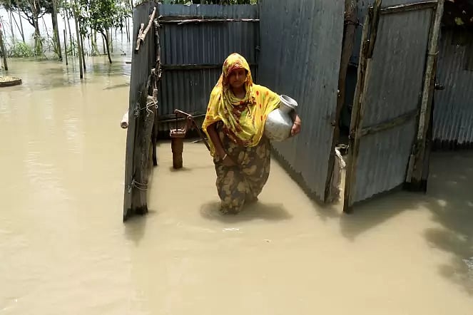 A woman collects water from an inundated tube well amid a crisis of drinking water  in Kamalpur, Sariakandi of Bogura.