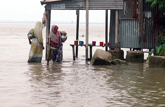 People collect water from an inundated tube well