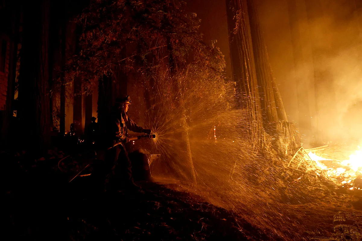 Cal Fire firefighter Anthony Quiroz douses water on a flame as he defends a home during the CZU Lightning Complex Fire in Boulder Creek, California, US, 21 August 2020.