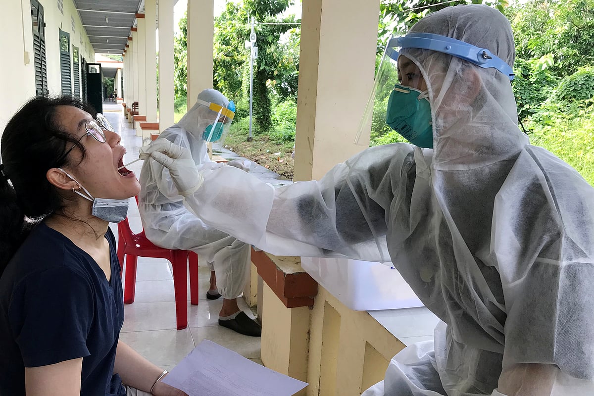 Medical specialists wearing protective hazmat suits take a swab sample to test for the coronavirus disease (COVID-19) from a woman repatriated from Singapore at a military base in southern Mekong delta Dong Thap province, Vietnam on 8 August 2020