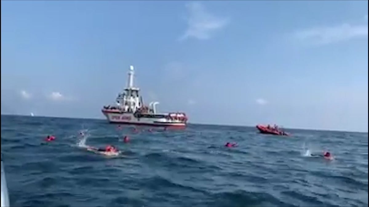 Migrants swim away from Spanish rescue ship Open Arms after more than 70 of them jumped from the ship to attempt to reach the coast, at sea near Palermo