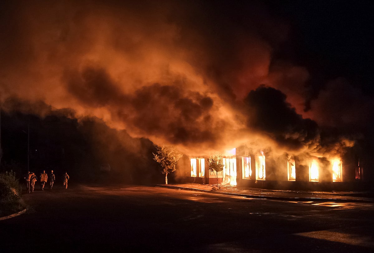Men walk near a shop on fire following recent shelling during a military conflict over the breakaway region of Nagorno-Karabakh in Stepanakert
