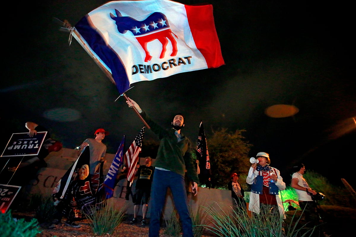A Biden supporter waves a Democrat flag in opposition of a Republican-led protest on the Nevada vote by Donald Trump supporters outside Clark County Election Department on 5 November, 2020, in North Las Vegas.