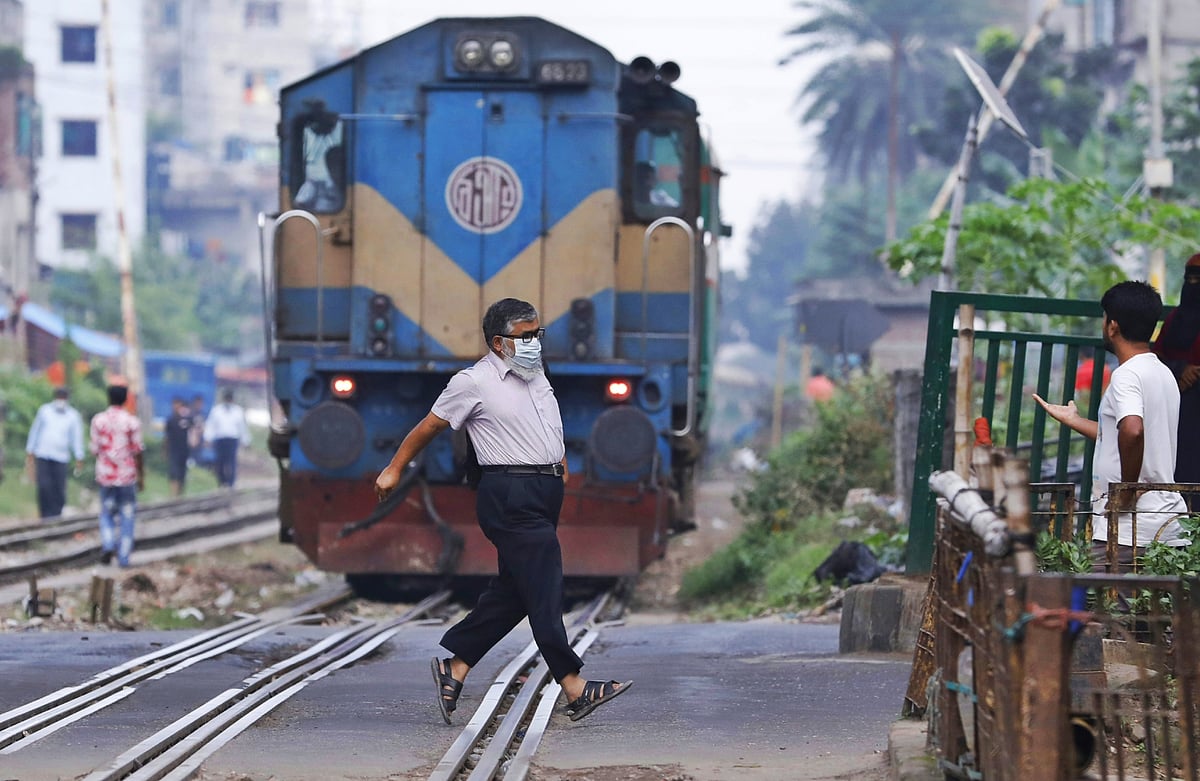 A man hurriedly crosses a railway track as a speedy train arrives in Maghbazar, Dhaka on 3 November 2020