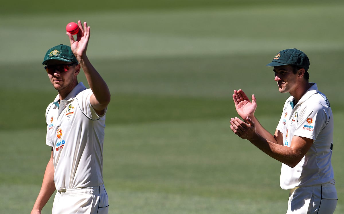 Australia's Josh Hazlewood (L) is applauded by fellow paceman Pat Cummins (R) after taking five Indian wickets as India is dismissed for only 36 runs on the third day of the first cricket Test match between Australia and India played in Adelaide on 19 December 2020