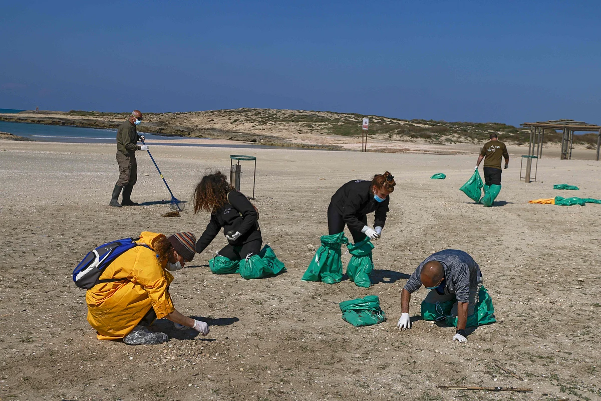 Israel volunteers clean the contaminated HaBonim beach, south the port city of Haifa, on 21 February, 2021