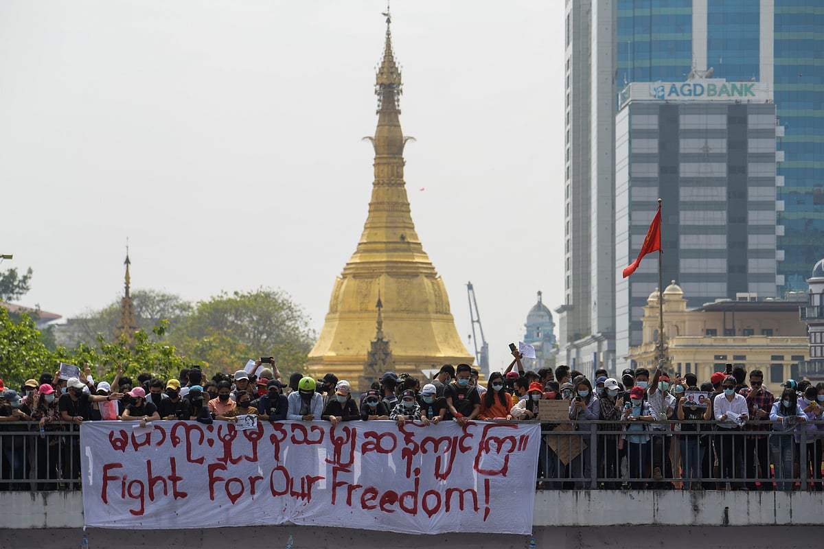 People stand next to a banner during a rally to protest against the military coup and to demand the release of elected leader Aung San Suu Kyi, in Yangon, Myanmar, 8 February, 2021