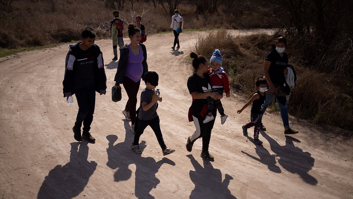 Migrant families walk down a dirt road after crossing the Rio Grande River into the United States from Mexico in Penitas, Texas, US, on 5 March 2021