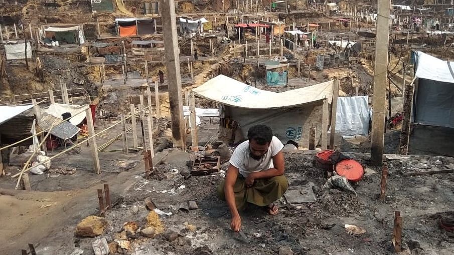 Mohammed Harun, 27, a Rohingya teacher who lost his parents in a deadly fire in Bangladesh camps, sifts through the charred remains of his hut in Cox's Bazar, Bangladesh, on 24 March 2021