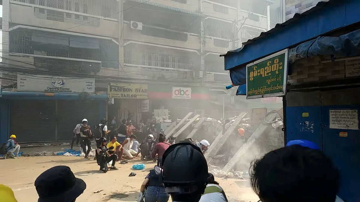 Protesters cover behind a makeshift barricade facing police in Hlaing Township, Yangon, Myanmar on 17 March 2021, in this still image from a social media video obtained by Reuters