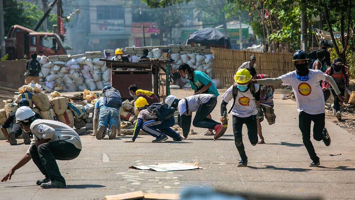 Protesters run during a crackdown by security forces on a demonstration against the military coup in Yangon's Thaketa township on 19 March 2021