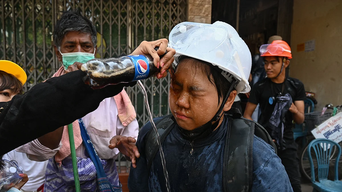 A protester has a Pepsi soft drink poured on their face in an attempt to stop the irritant effects of tear gas fired by police during a demonstration against the military coup in Yangon on 7 March 2021.