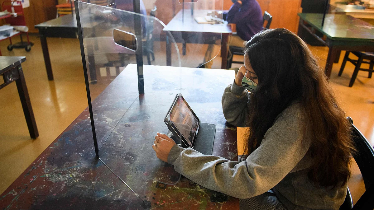 Students work behind protective barriers during an art class as they return to in-person learning at St. Anthony Catholic High School during the Covid-19 pandemic on 24 March 2021 in Long Beach, California
