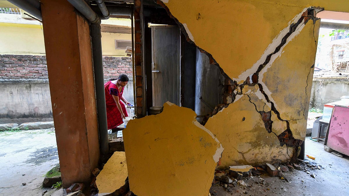 A woman collects water from a tap near a collapsed wall at an apartment building in Guwahati on 28 April 2021, after a strong earthquake hit Assam in northeastern India, damaging buildings, but there were no immediate reports of casualties
