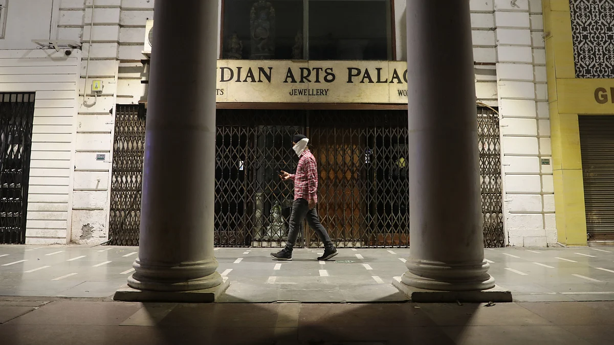 A man walks past closed shop after night curfew imposed by the state government, to curb the spread of Covid-19, as a preventive measure against the Covid-19 coronavirus, in New Delhi on 6  April 2021