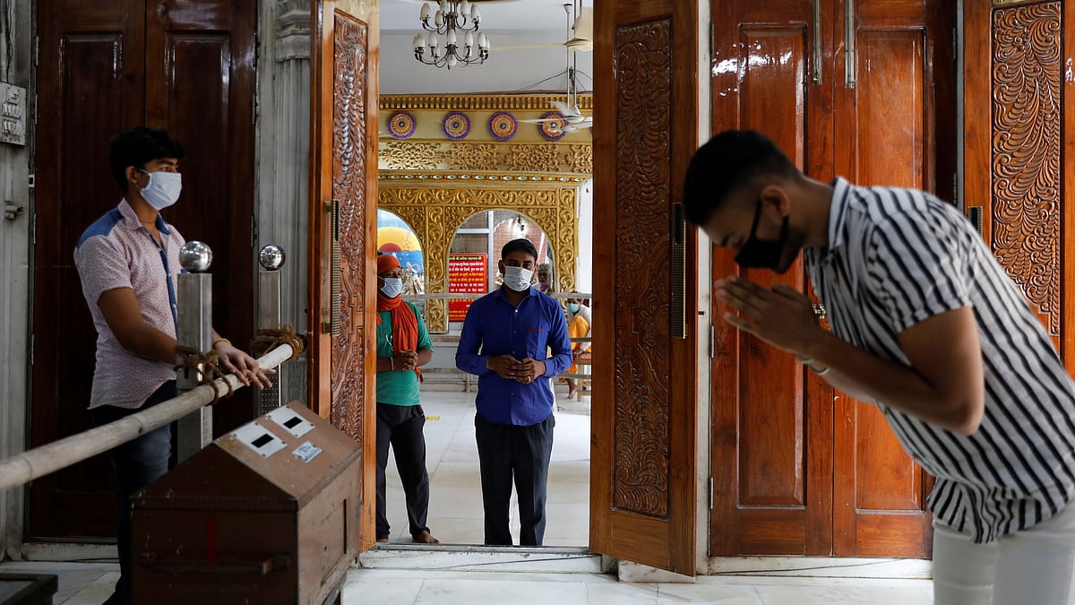 Men wearing protective masks wait to pray as they maintain social distancing inside a temple after the opening of most of the religious places after India eases lockdown restrictions that were imposed to slow the spread of the coronavirus disease (COVID-19), in New Delhi, India, 8 June 2020.