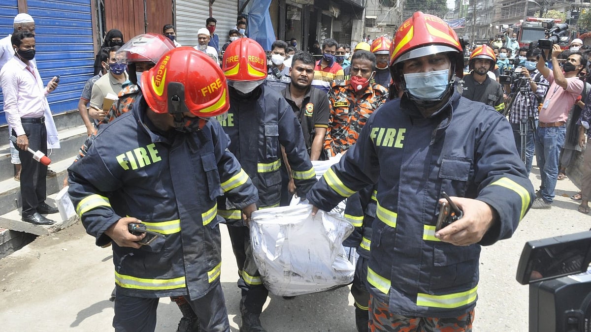 Fire service men carry the body of a person burned dead in the fire at a residential building in Armanitola, Dhaka on 23 April 2021