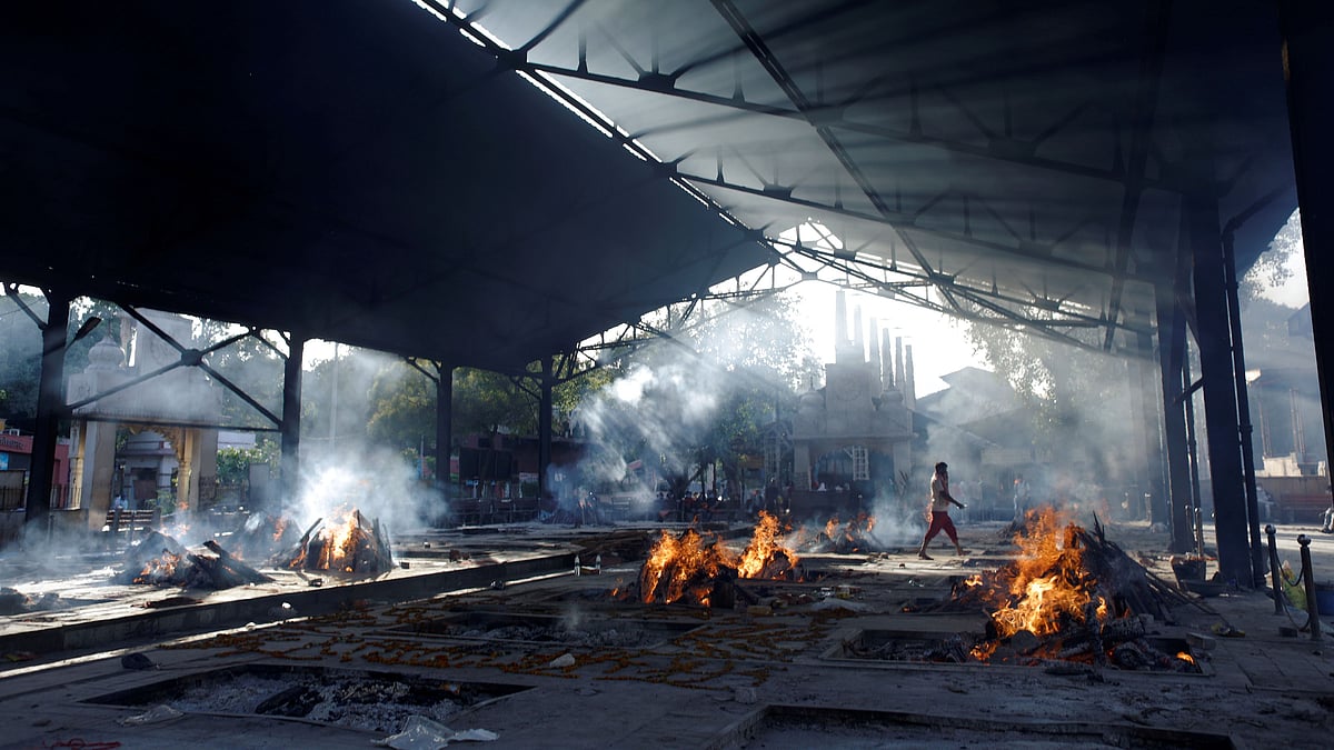 A person walks past funeral fires of those who died from the coronavirus disease (COVID-19) at a crematorium in New Delhi, India on 24 April 2021