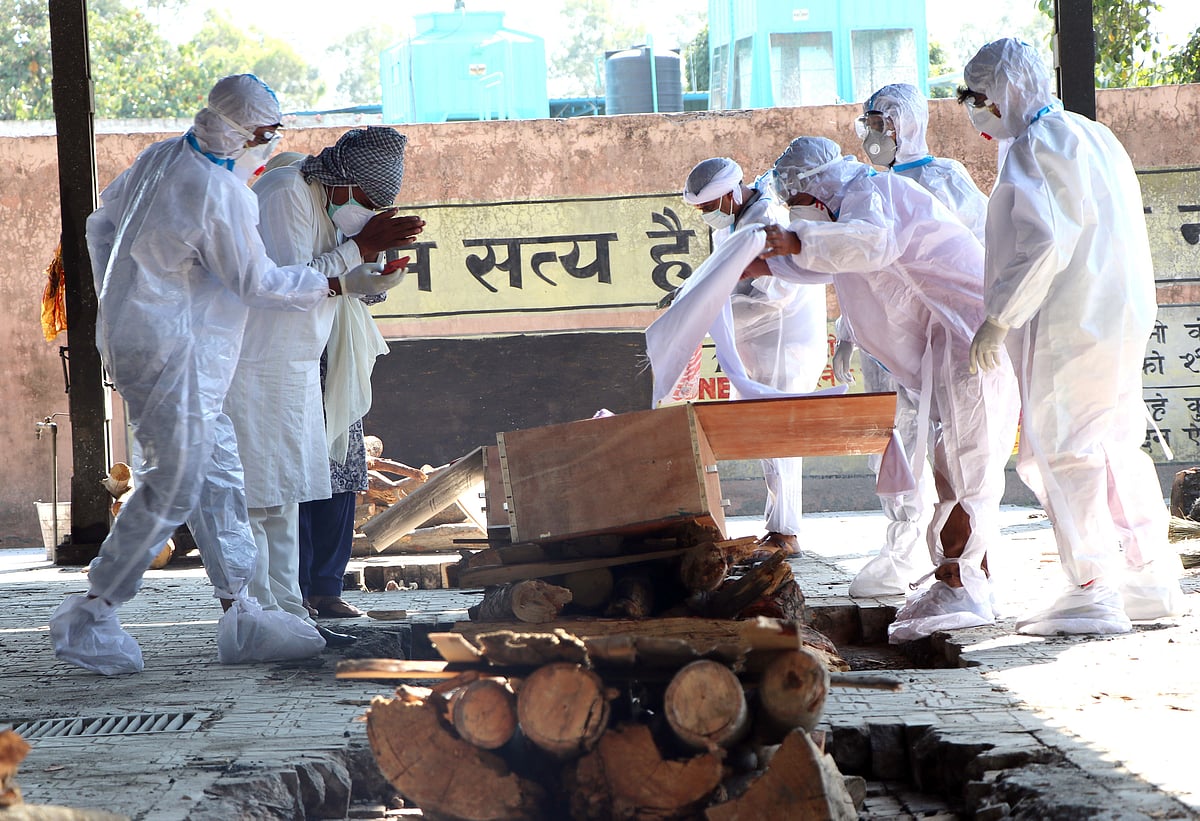 Family members wearing PPE kit perform the last rites of a Covid-19 victim at Shastri Nagar Cremation Ground, in Jammu on 27 May 2021