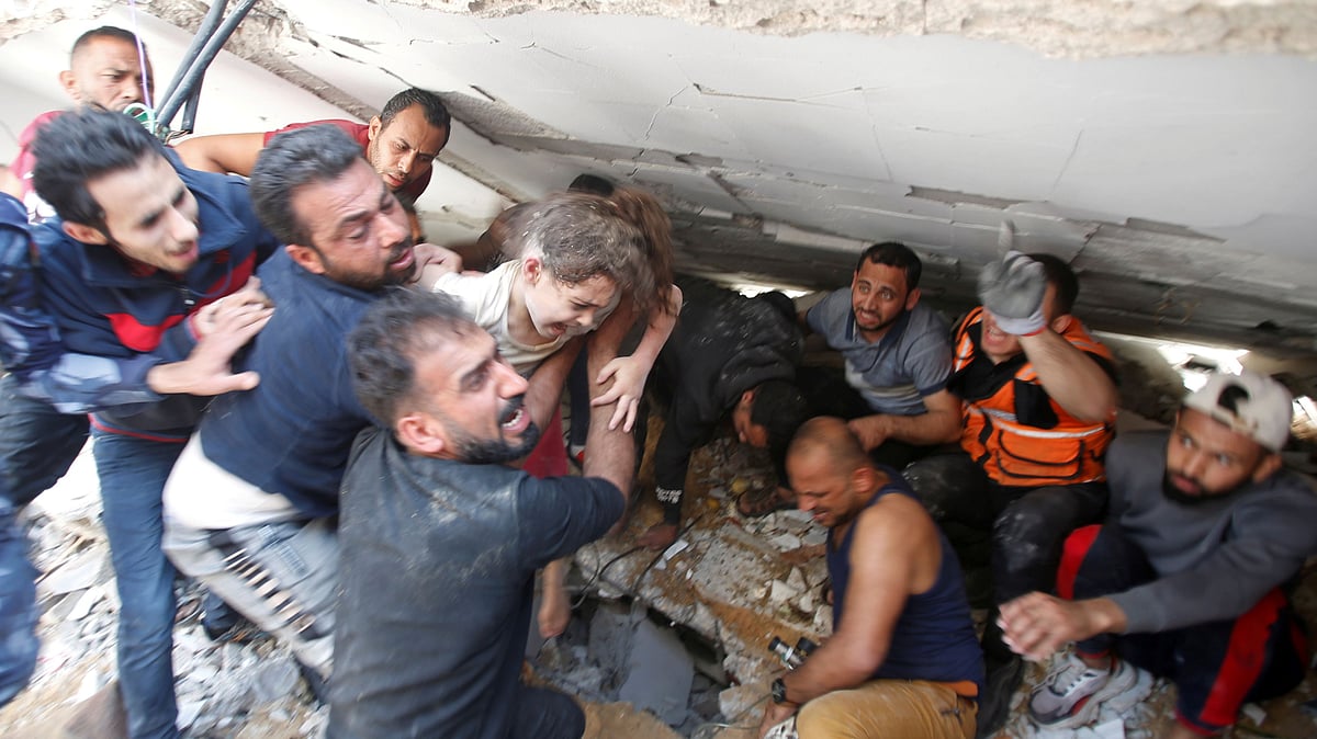 Rescuers carry a girl as they search for victims amid rubble at the site of Israeli air strikes, in Gaza City 16 May 2021