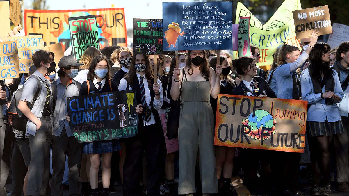 School students hold up placards as they march at a School Strike 4 Climate rally during a mass school strike for climate action in Melbourne on May 21, 2021.