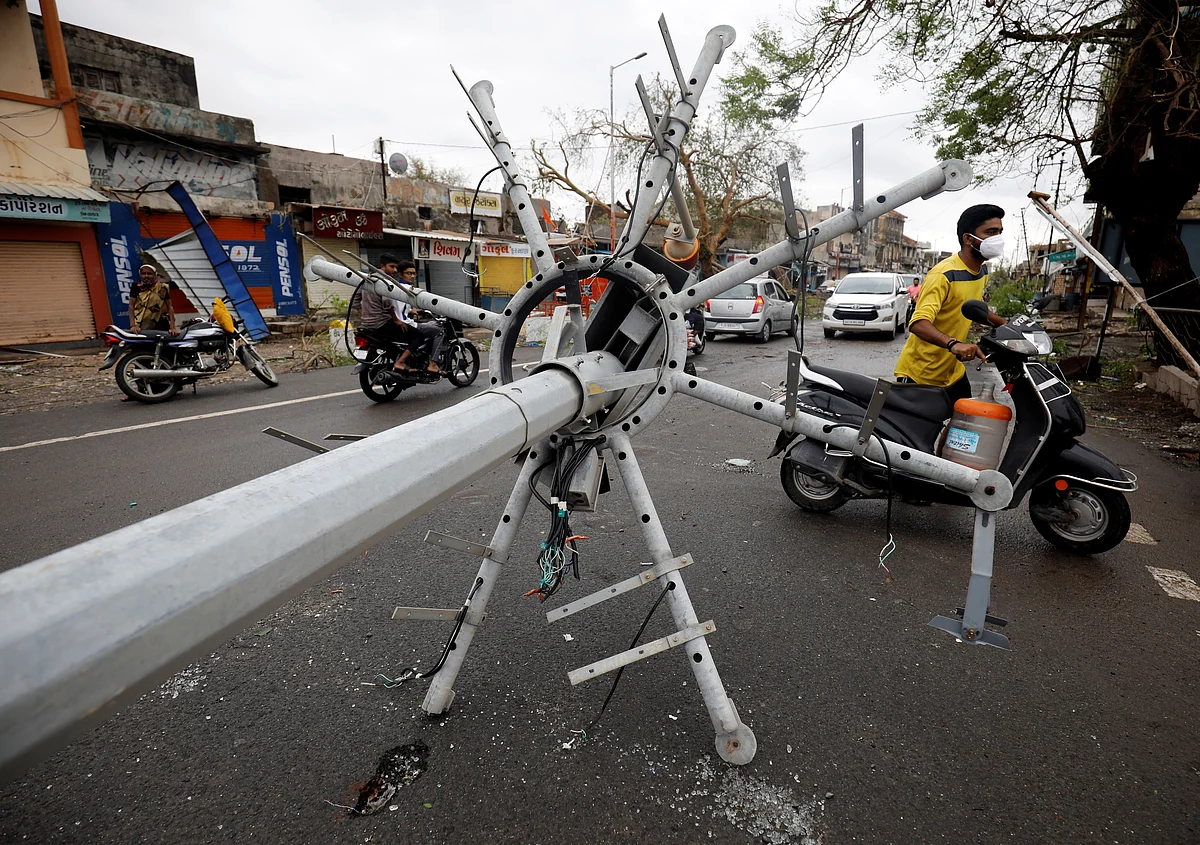 Motorcyclists move past a fallen street light pole after cyclone Tauktae hit, in Una, in the western state of Gujarat, India, on 18 May 2021
