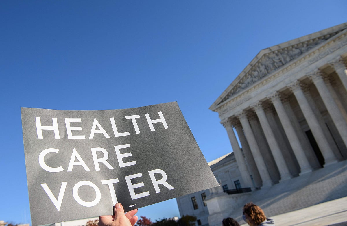 In this file photo taken on 10 November, 2020, demonstrator holds a sign in front of the US Supreme Court in Washington, DC, as the court opened arguments in the case over the constitutionality of the 2010 Affordable Care Act