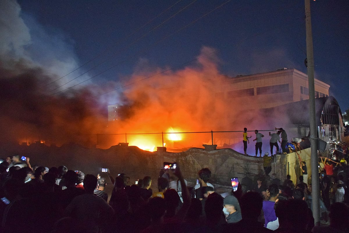 People take images of flames as a massive fire engulfs the coronavirus isolation ward of Al-Hussein hospital in the southern Iraqi city of Nasiriyah, late on 12 July, 2021