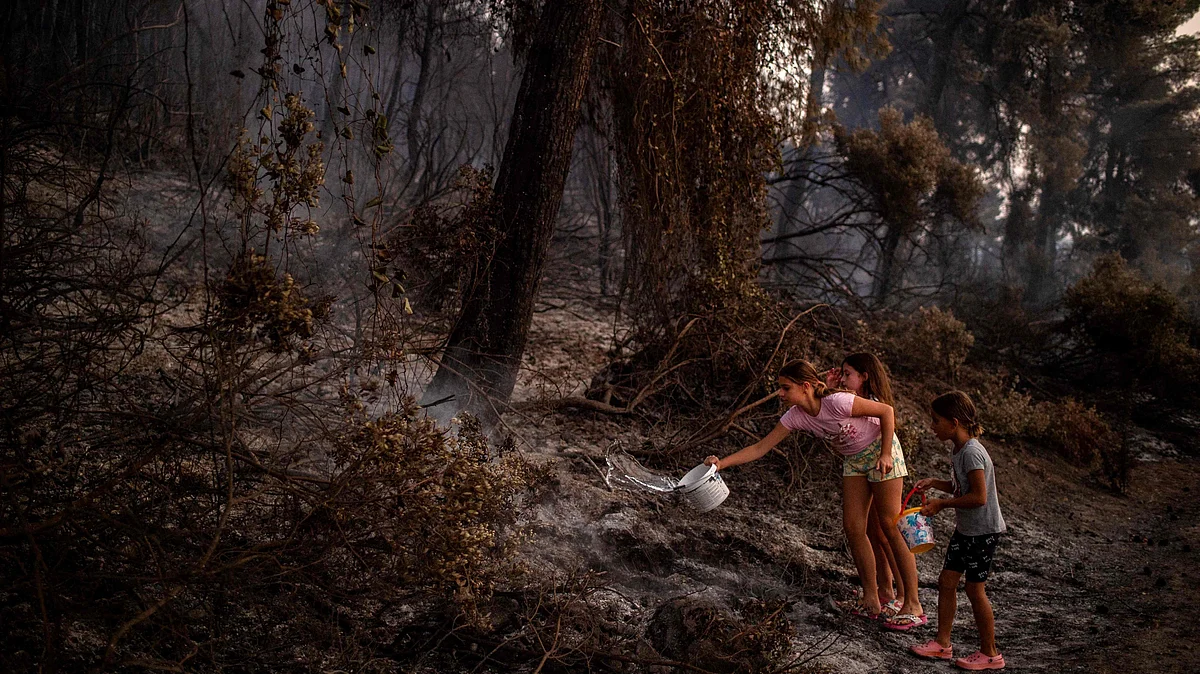 Children pour water after a forest fire near in the village of Kastri on Evia (Euboea) island, on 10 August, 2021