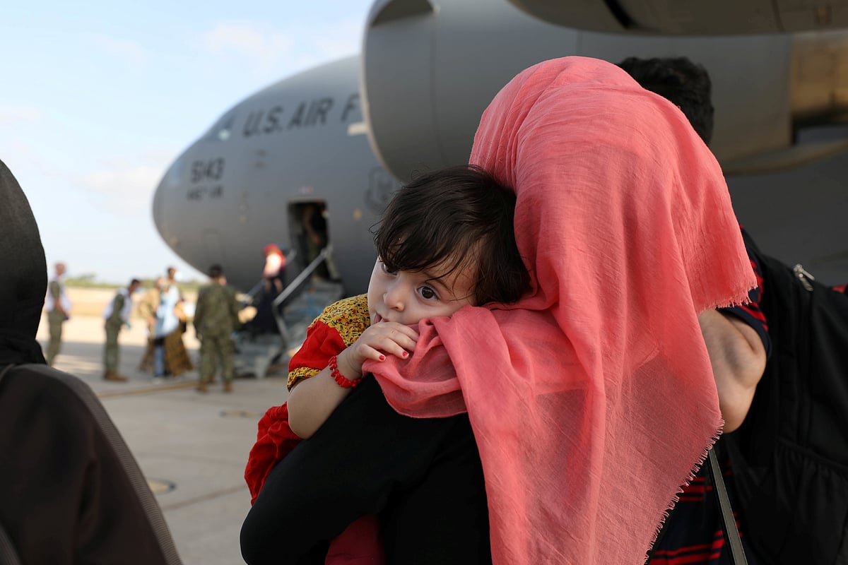 Evacuees from Afghanistan watch others disembark the aircraft after arriving at Naval Station (NAVSTA) Rota, Spain on 27 August 2021