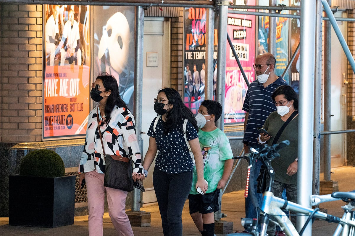 People walk near posters of theatre shows while they wear masks to prevent against the spread of the coronavirus disease (COVID-19), as the highly transmissible Delta variant has led to a surge in infections, in New York City, US on 30 July  2021.
