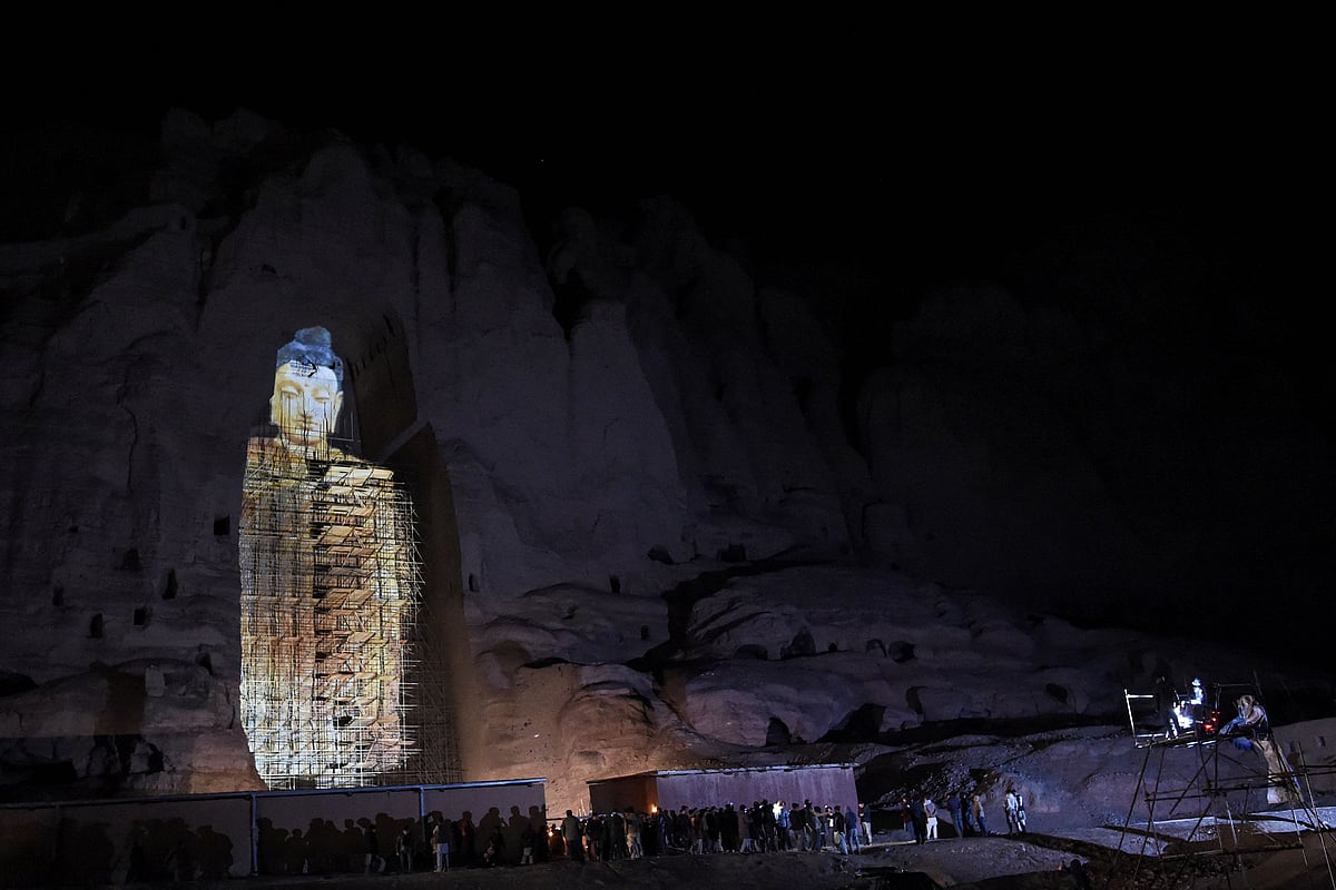 In this file photo taken on 9 March, 2021, people watch a three-dimensional projection of the 56 metres-high Salsal Buddha at the site where the Buddhas of Bamiyan statues stood before being destroyed by the Taliban in March 2001, in Bamiyan province