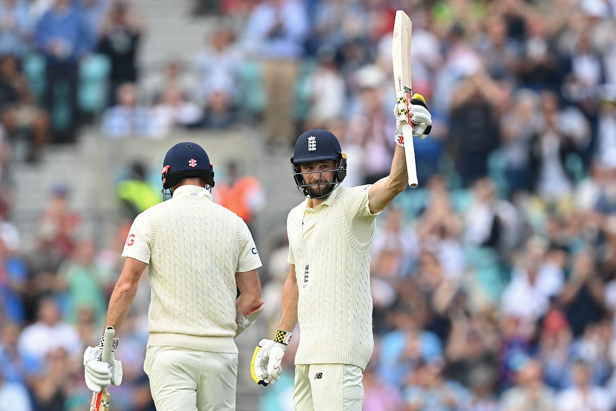 England's Chris Woakes (R) celebrates reaching his half century during play on the second day of the fourth cricket Test match between England and India at the Oval cricket ground in London