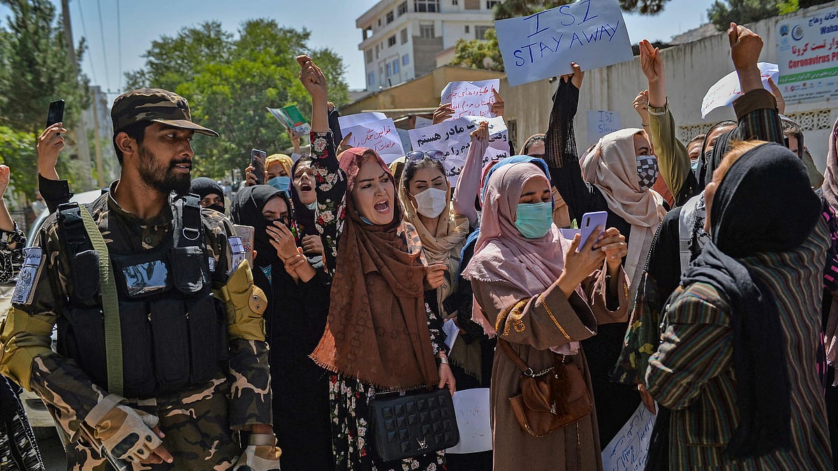 A Taliban fighter stands guard as Afghan women shout slogans during an anti-Pakistan protest rally, near the Pakistan embassy in Kabul on 7 September 2021.