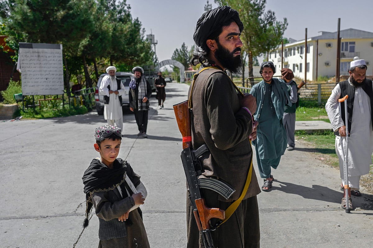 An Afghan boy stands next to a member of the Taliban in front of the Pul-e-Charkhi prison in Kabul on 16 September 2021.