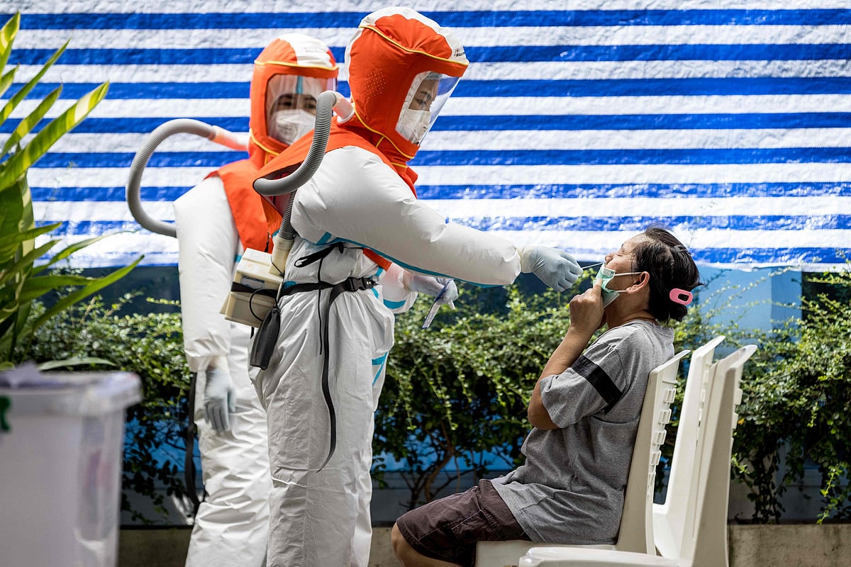 A health worker wearing personal protective equipment (PPE) administers a Covid-19 coronavirus nasal swab during a round of testing of workers outside a market in Bangkok 4 September, 2021