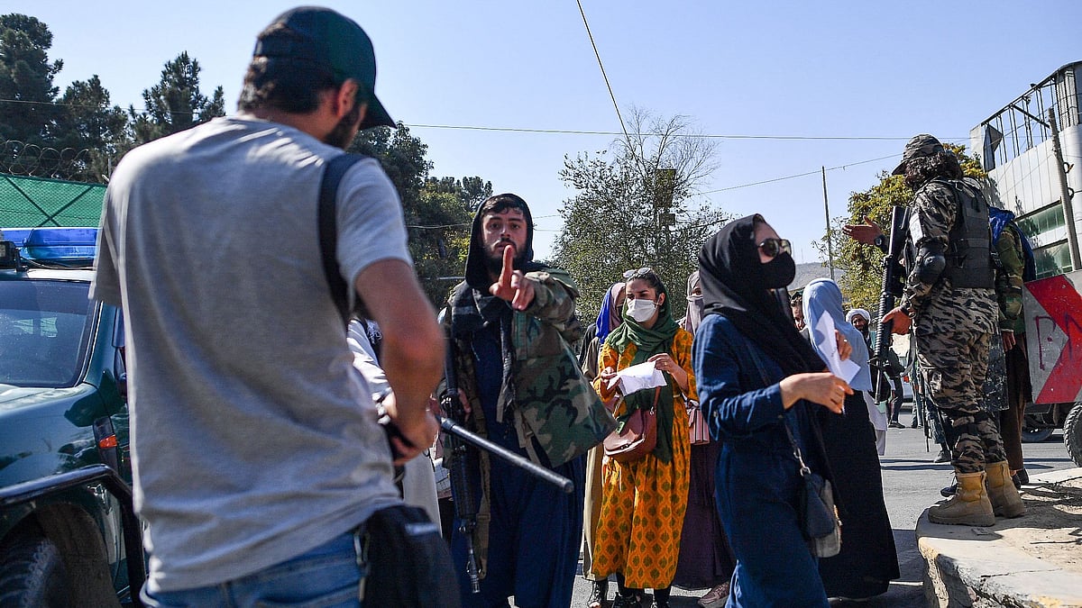 A Taliban members (C) gestures towards journalists covering a women's rights protest in Kabul on 21 October, 2021