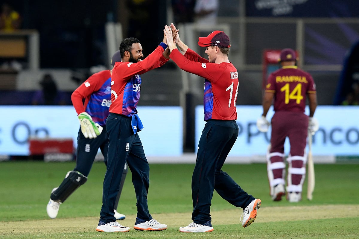 England's Adil Rashid (L) celebrates with his captain Eoin Morgan after taking the wicket of West Indies' Ravi Rampaul (R) during the ICC men’s Twenty20 World Cup cricket match between England and West Indies at the Dubai International Cricket Stadium in Dubai on October 23, 2021.